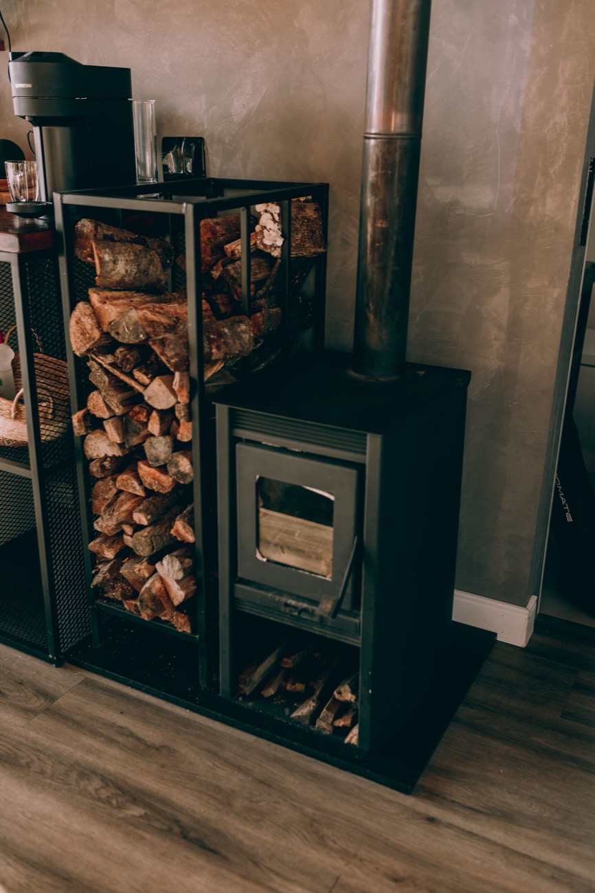 Poêle à bois allumé à côté d'une réserve de bûches
